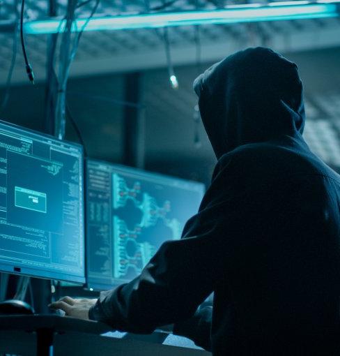 黑客从他的地下藏身处侵入公司数据服务器. 这个地方气氛阴暗，有多个显示器，到处都是电缆.